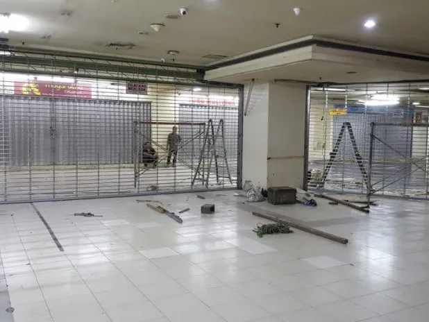 Teknisi melumasi as gulung rolling door gudang